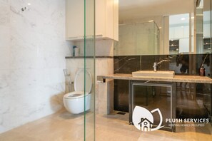 A modern bathroom with a toilet, sink, and glass shower enclosure.