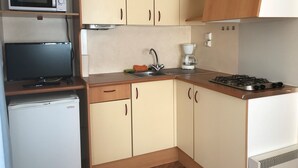 Cocina compacta equipada con microondas, estufa, pileta y un refrigerador pequeño.