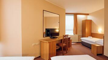 A hotel room with a bed, a desk with a chair, a television, and a wardrobe.
