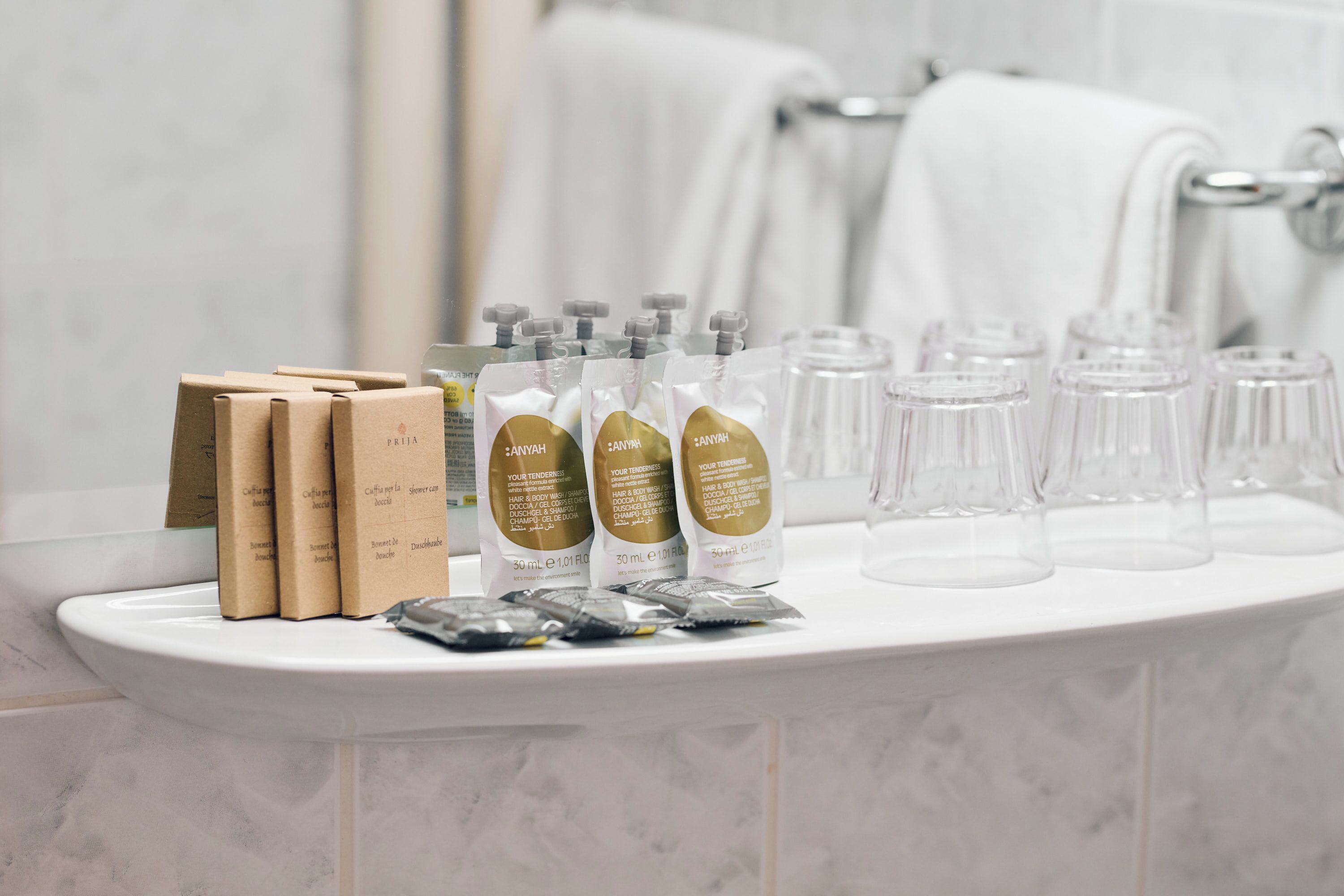 A bathroom counter with toiletries including brown boxes, bottles, and clear glasses.