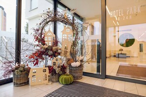 Entrada de hotel con una decoración ornamental que incluye un adorno de guirnalda, figuras con forma de casa y plantas en macetas.