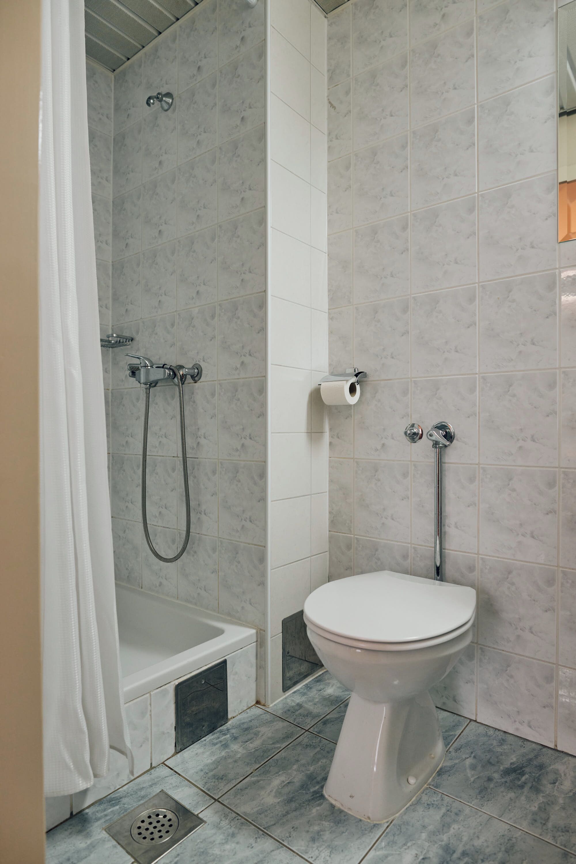 Un baño con ducha, inodoro y un perchero para toallas.
