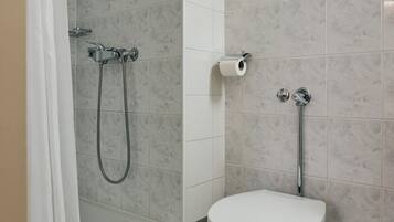 Un baño con ducha, inodoro y un perchero para toallas.