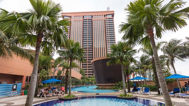 A hotel with a large pool surrounded by palm trees and lounge chairs. - Times Square 1 by Plush (Kuala Lumpur)