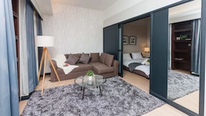 A modern living room with a sectional sofa, a glass coffee table, and a large mirror. - Times Square 1 by Plush (Kuala Lumpur)