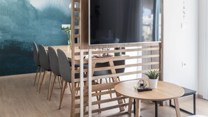 Un espace repas moderne avec une cloison en bois, une table ronde agrémentée d’une plante en pot et un téléviseur à écran plat fixé sur la cloison.