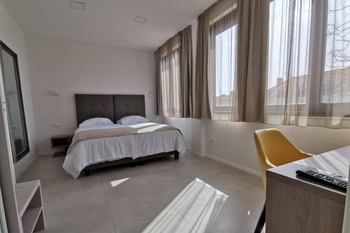 A modern hotel room with a bed, a desk, and a chair.