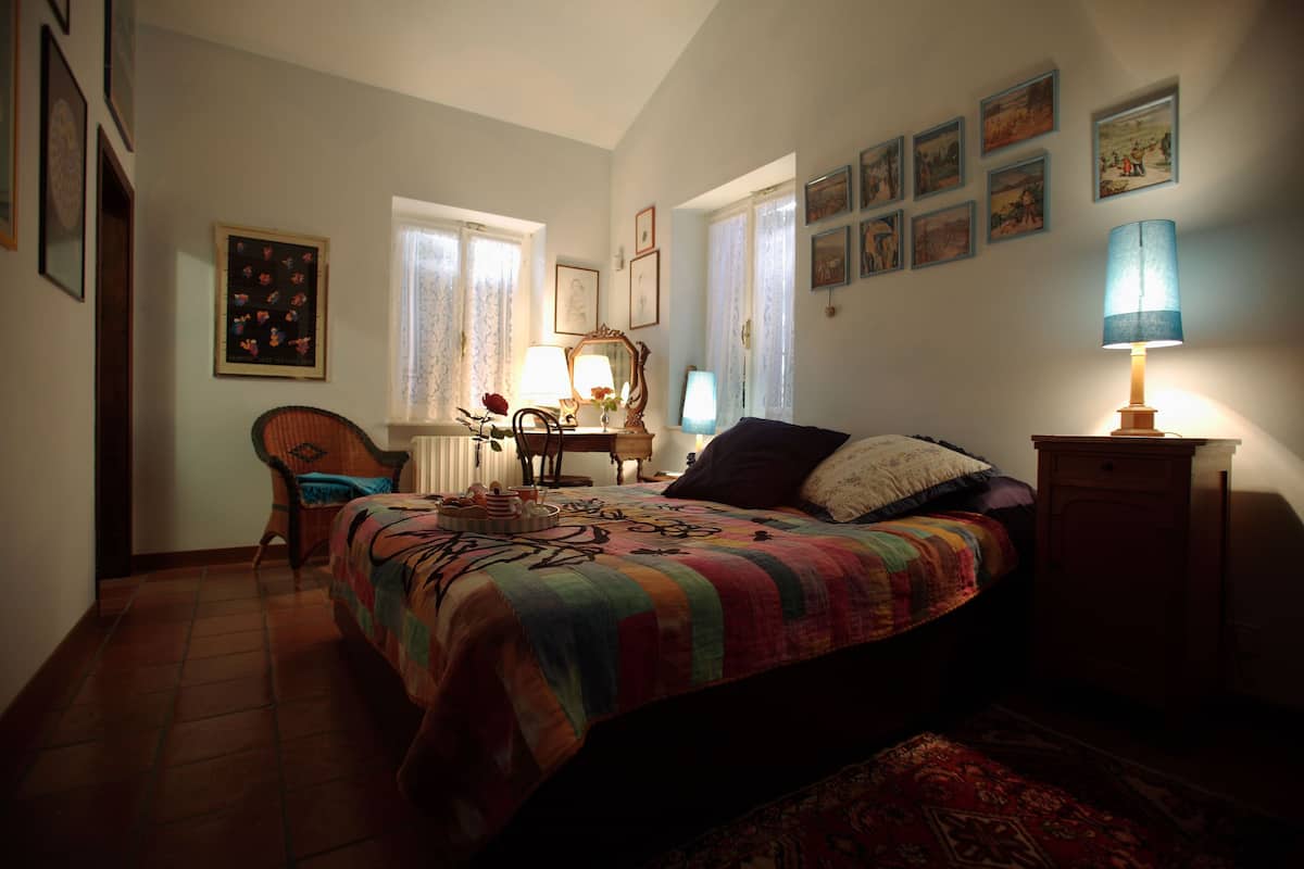 A bedroom with a bed, a chair, a desk, and a lamp.