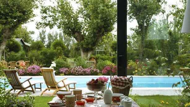A table set outdoors with a view of a pool and garden. - Villa Mirella Beach (Fermo)
