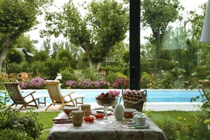 A table set outdoors with a view of a pool and garden. - Villa Mirella Beach (Fermo)