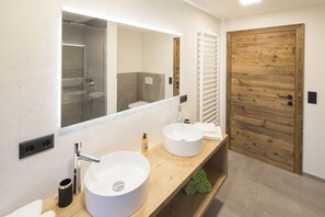Een moderne badkamer met twee wastafels, een grote spiegel en een houten deur.