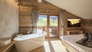 Un baño moderno con una bañera independiente, un espejo grande y suelo de madera.