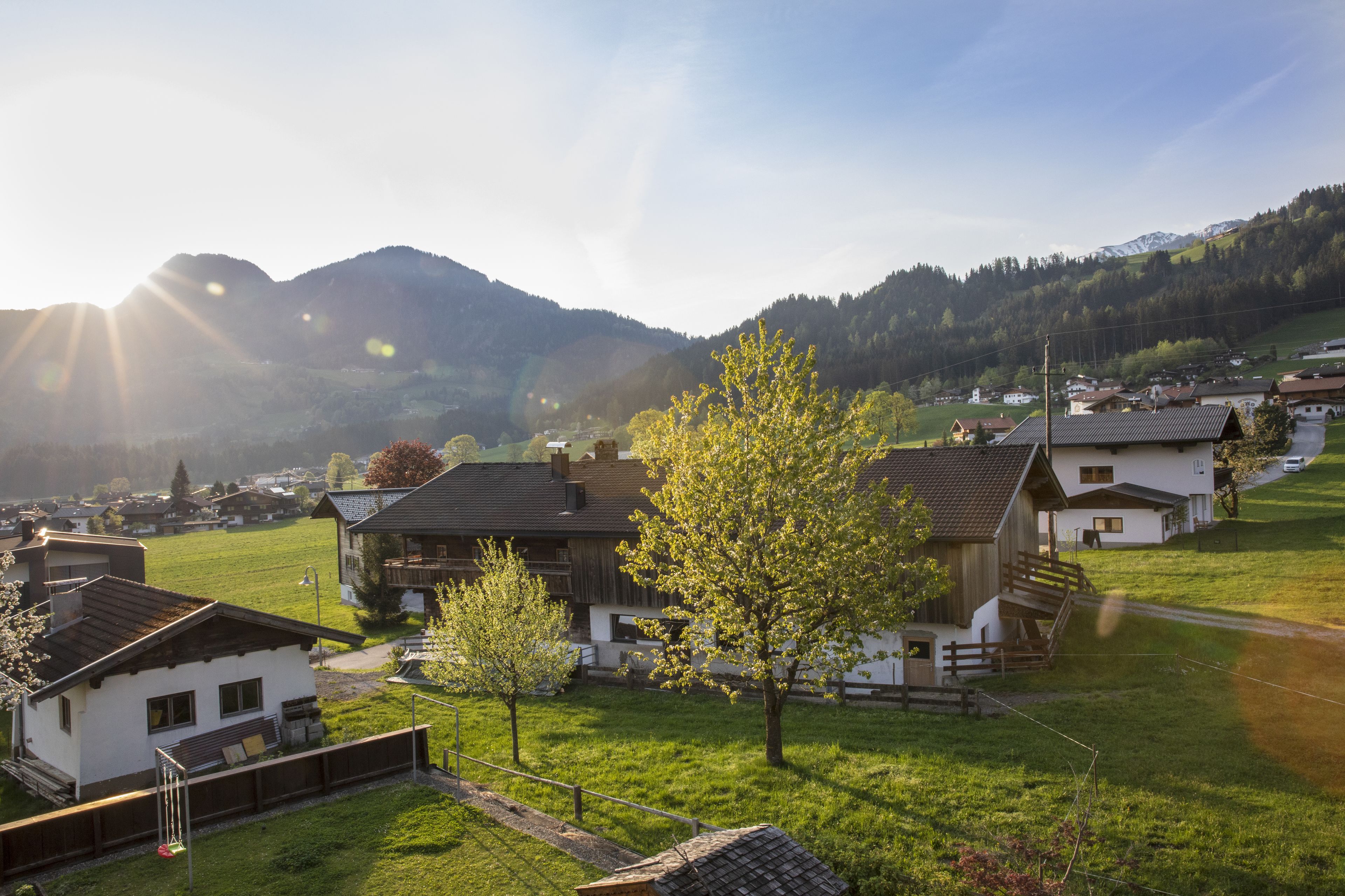 Ein ländliches Dorf mit Häusern, einem klaren Himmel und Bergen im Hintergrund.