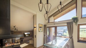 Una cocina moderna con mesa de comedor de vidrio, luces colgantes y vistas al exterior.