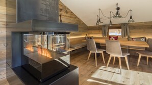 Una cocina moderna con estufa de vidrio, paredes de madera y un comedor con sillas y un banco.