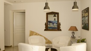 A modern living room with white furniture, a large mirror, and two pendant lights. - B&B Nencioli (Castellammare del Golfo)