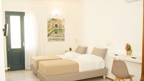 A bedroom with two beds, a desk, a chair, a door, and a painting on the wall. - B&B Nencioli (Castellammare del Golfo)