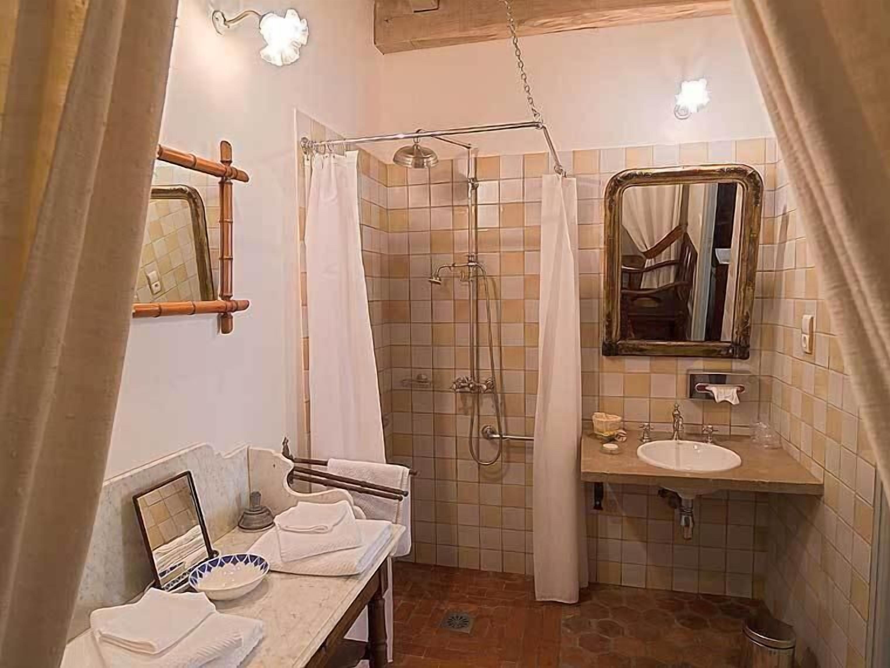 Un baño con ducha, lavamanos, espejo y barra para toallas.
