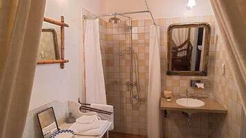 Un baño con ducha, lavamanos, espejo y barra para toallas.