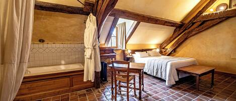 A rustic bedroom with a wooden ceiling, a bed, a small table, and a chair.