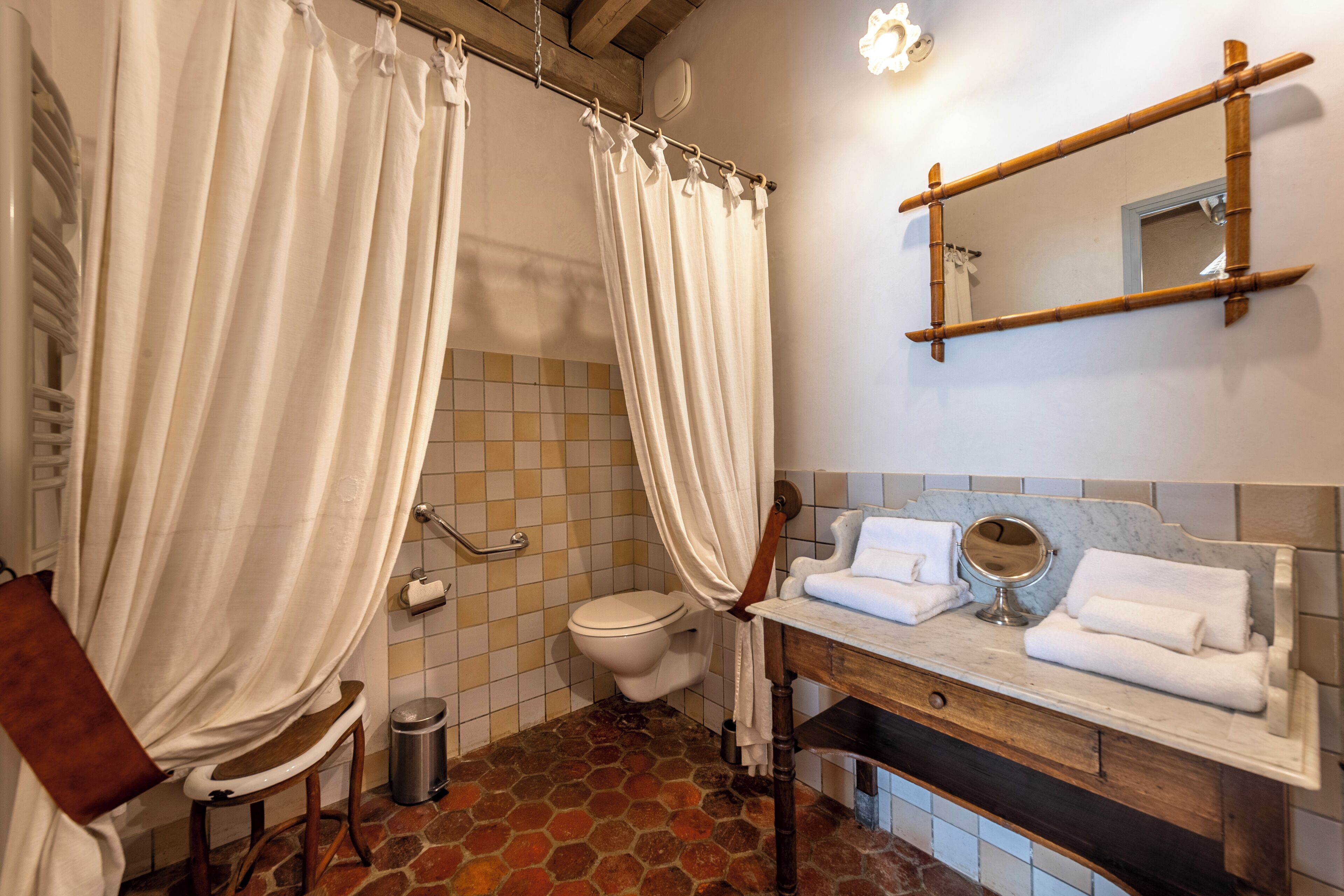 A bathroom with a toilet, a sink with a mirror, and a shower curtain.