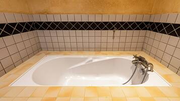 Una vasca da bagno con doccetta e flessibile, circondata da piastrelle gialle e bianche.