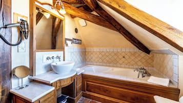 Un baño con tocador de madera, una bañera grande y un espejo.