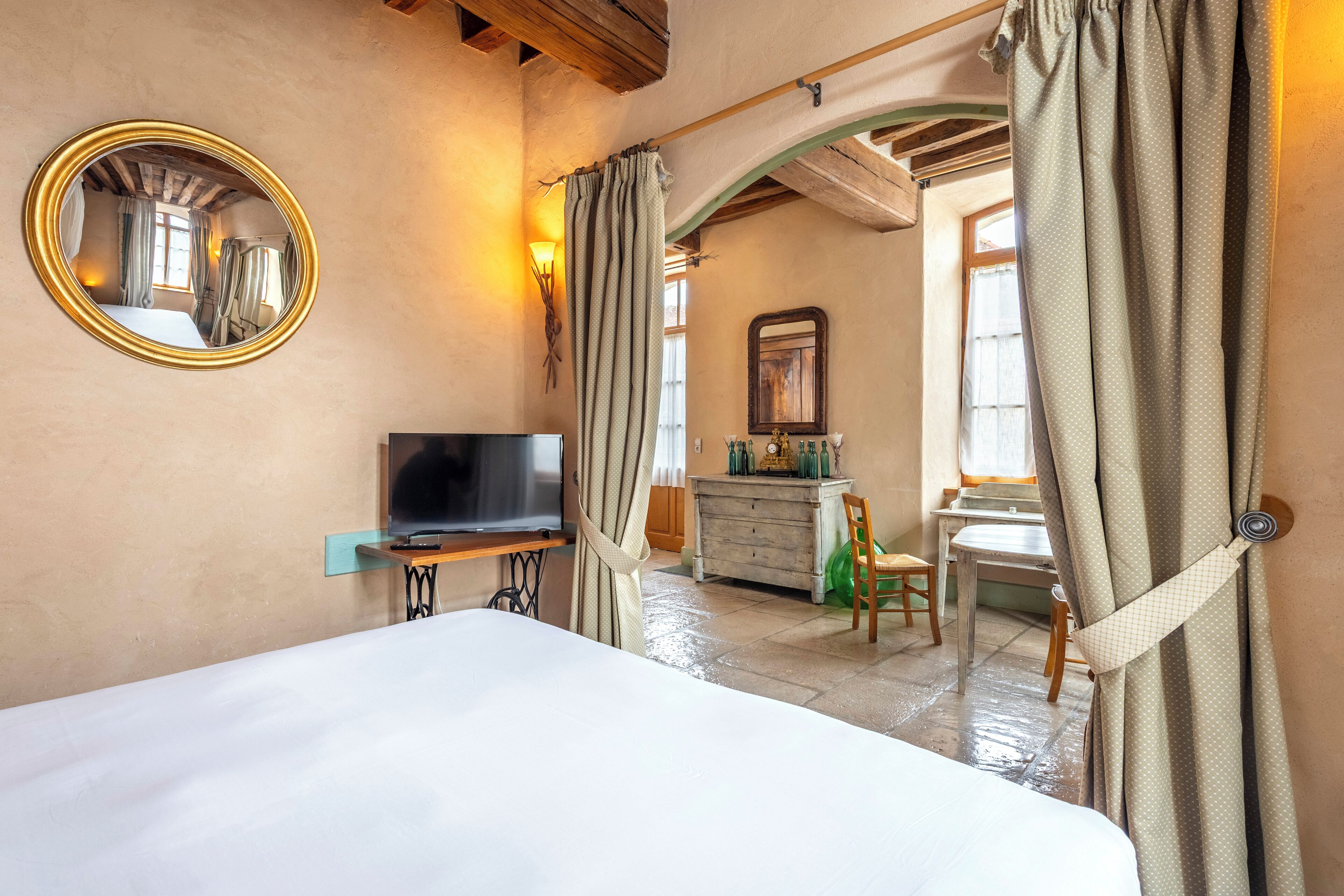 A hotel room with a bed, a television, a dresser, and a mirror.