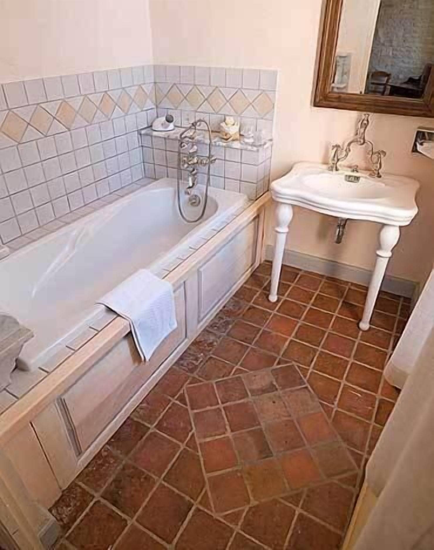 A bathroom with a bathtub, a sink, and a tiled floor.