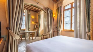 Una habitación de hotel con una cama grande, una mesa de comedor con sillas y cortinas.