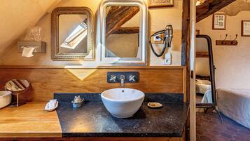 A bathroom with a wooden vanity, a white sink, and two mirrors.
