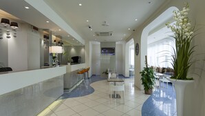 A modern hotel lobby with a reception desk, seating area, and a dining space. - Hotel Aurora Mare (Rimini)