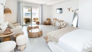 Ein geräumiges Hotelzimmer mit einem großen Bett, einem Sofa, einem Esstisch und einer Sitzecke mit Sesseln.