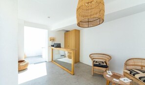 A modern room with a wooden desk, wicker furniture, and a hanging light fixture.