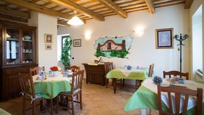 Ein Essbereich mit Holztischen und -stühlen, einer grünen Tischdecke und rustikaler Decke.