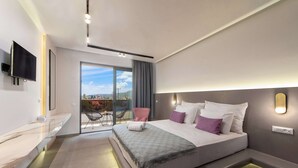 A modern hotel room with a large bed, a TV mounted on the wall, and a balcony with a view of the city. - Madison Boutique (Rhodes)