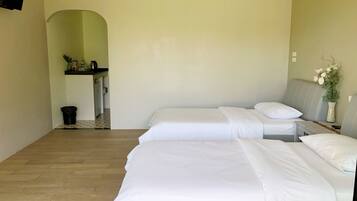 Habitación de hotel con dos camas, una kitchenette pequeña y piso de madera.