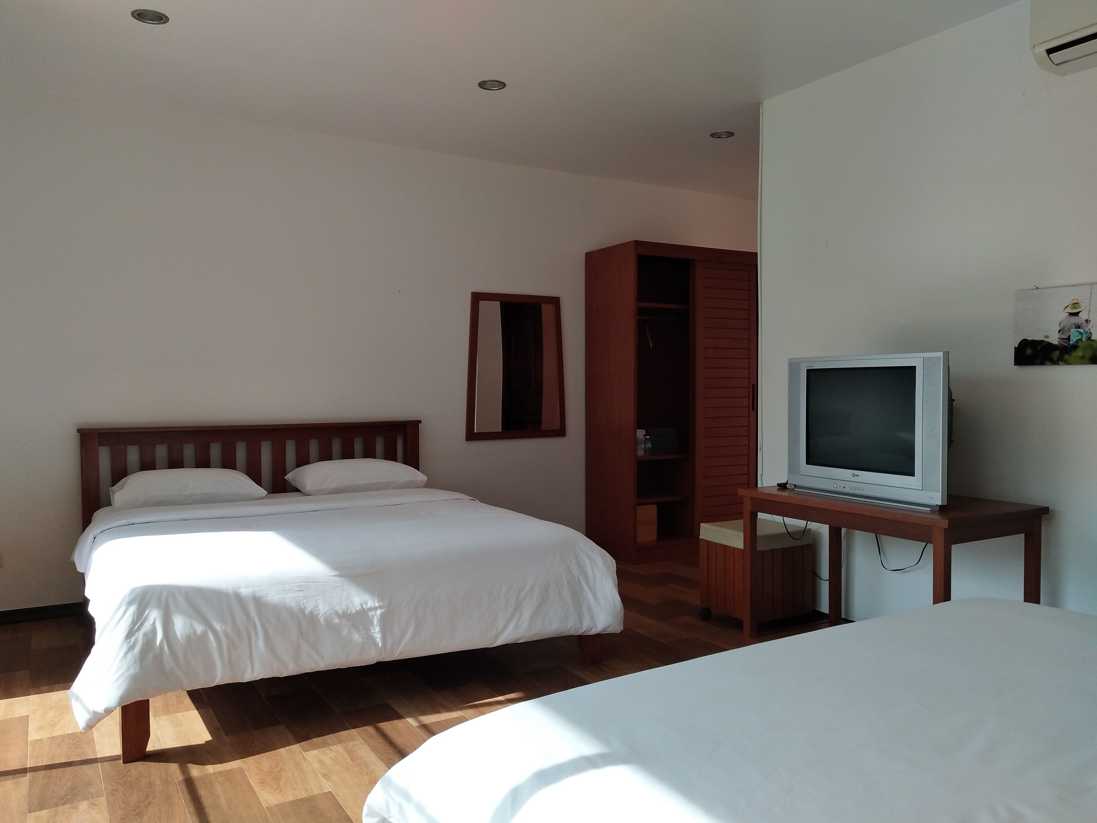 Een hotelkamer met een houten bed, een televisie op een houten plank en een kledingkast.