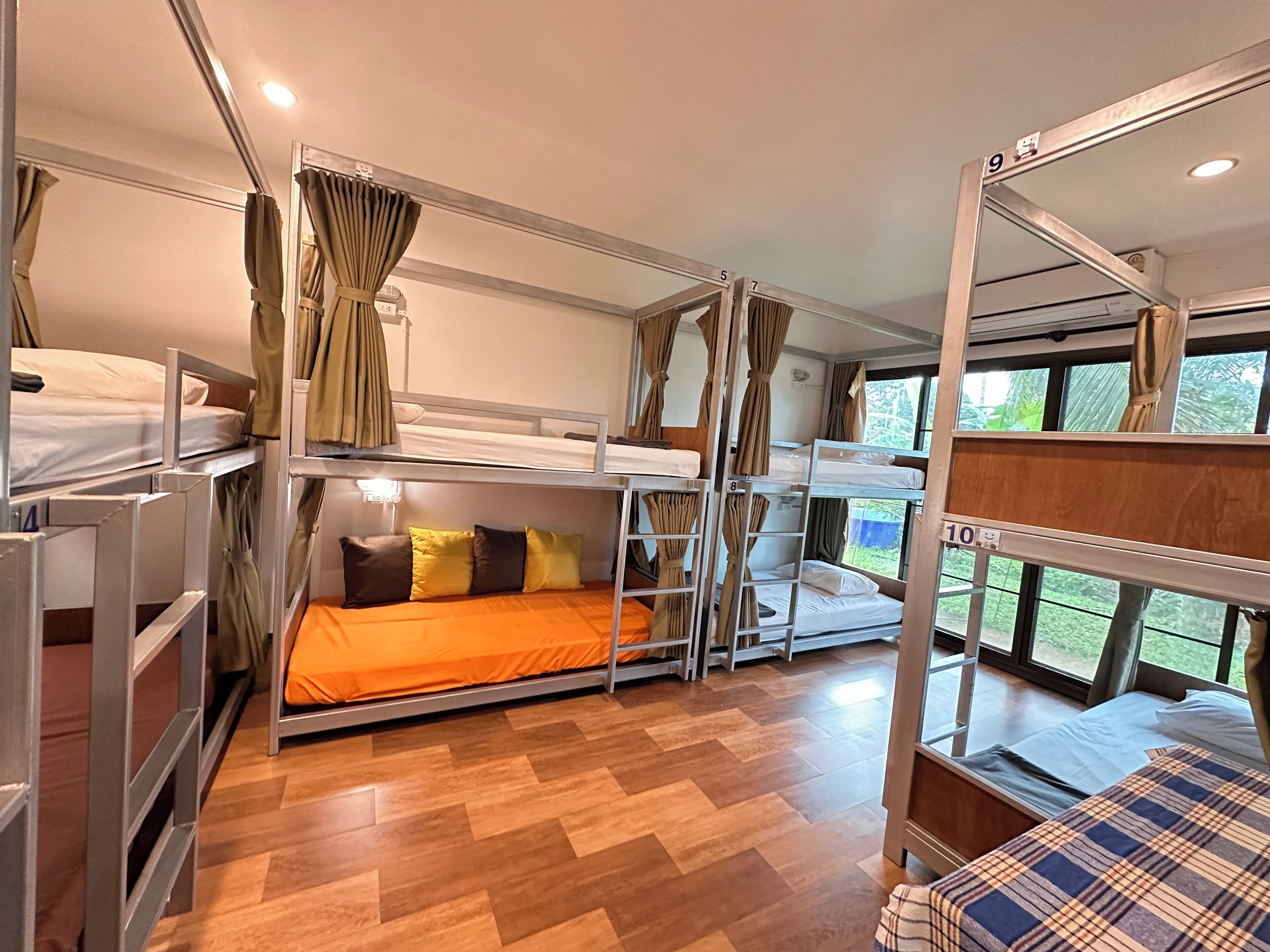 Habitación con literas múltiples, suelo de madera y cortinas.