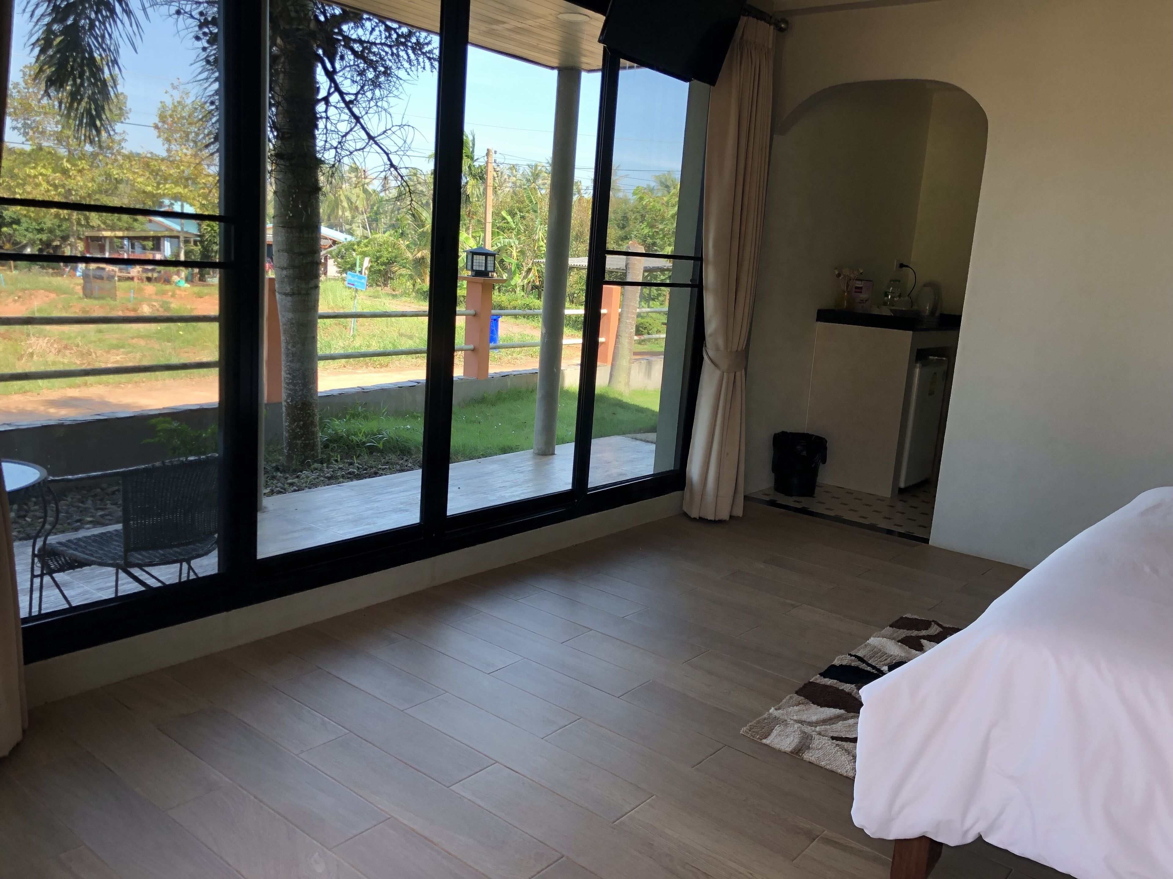 Un dormitorio con una ventana grande, una cama, una pequeña cocina y vistas al exterior.