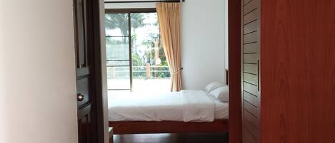 Un dormitorio con cama, ventana con cortinas y un armario de madera.