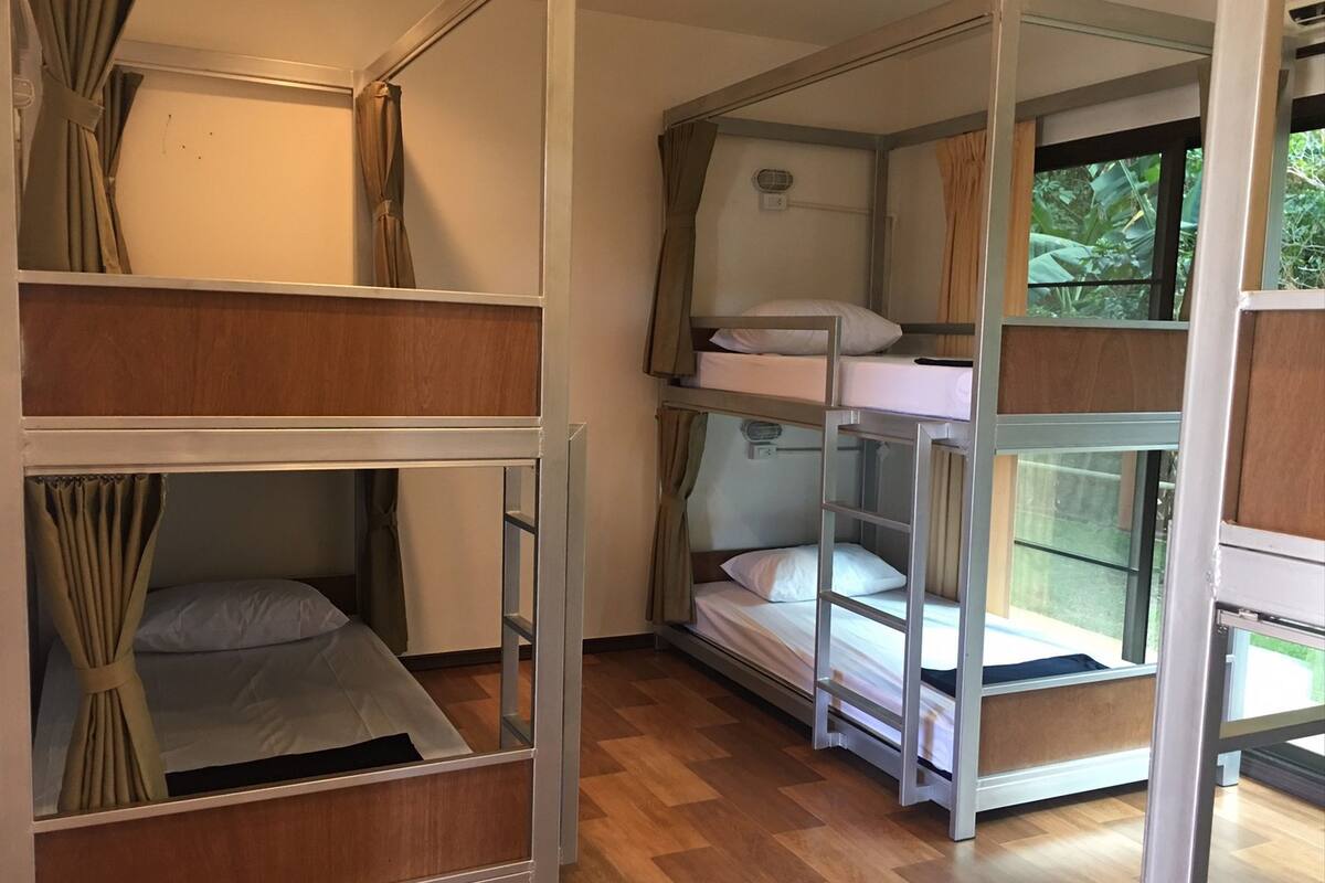 Een slaapkamer met stapelbed, raam en gordijnen.