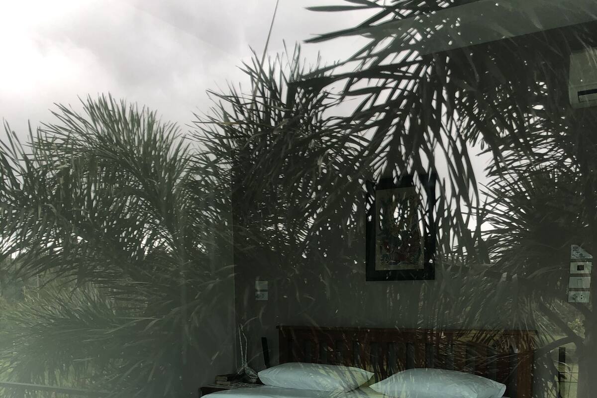 Een bed met een witte spreideken en een houten hoofdbord, geplaatst tegen een muur met een patroon.