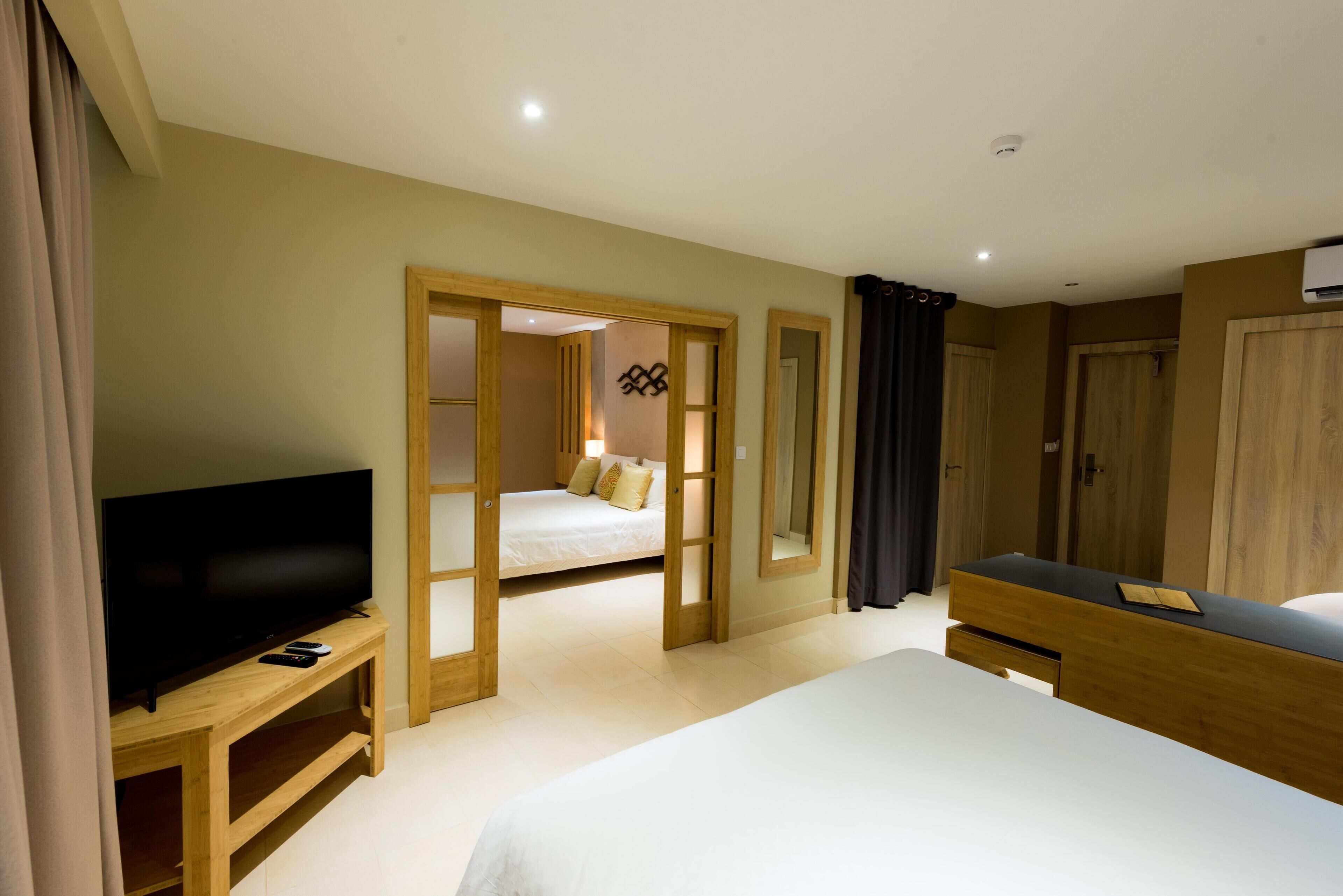 A hotel room with a large bed, a TV on a wooden stand, a bedside table, and a wardrobe.