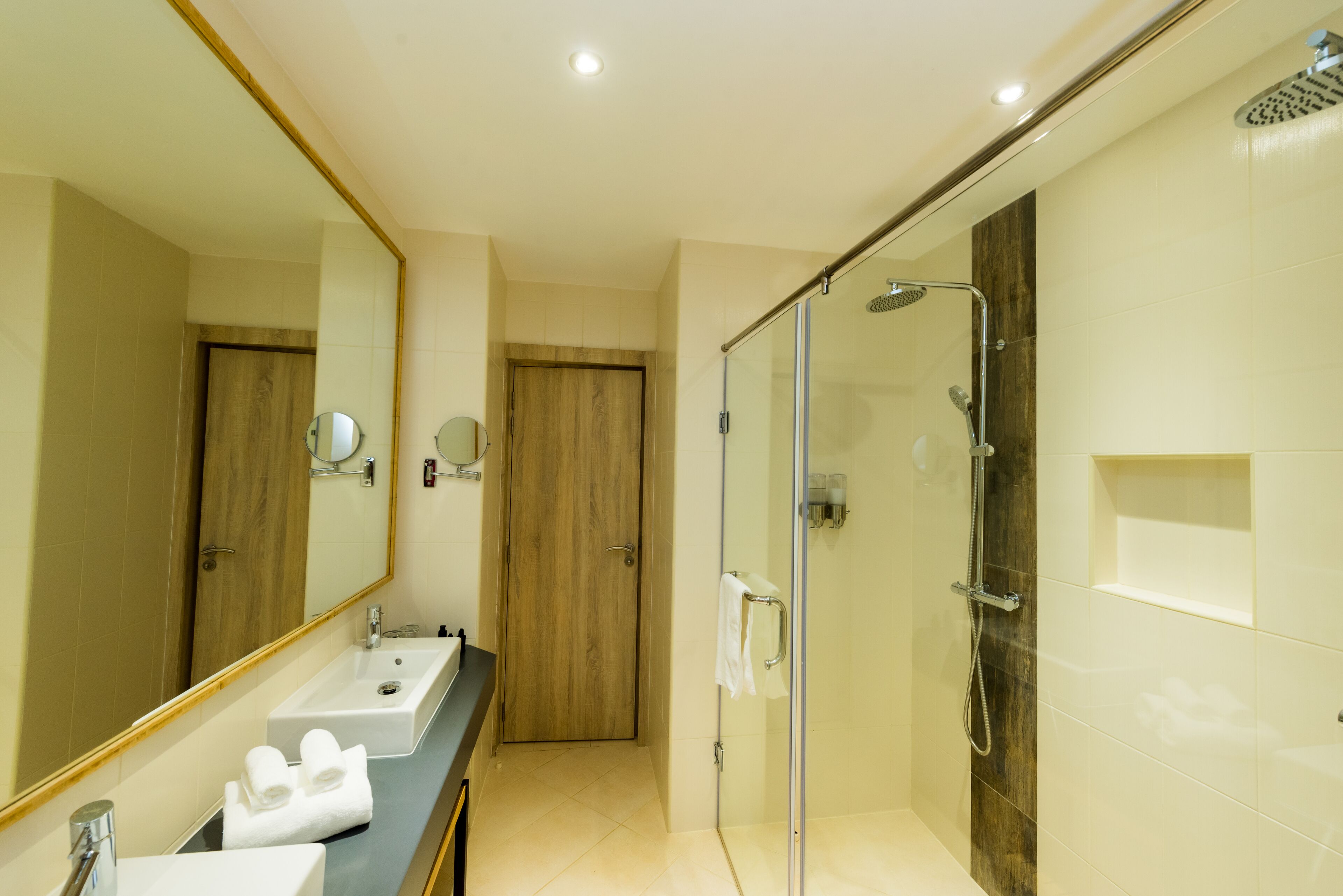 A modern bathroom with a glass-enclosed shower, a vanity with two sinks, and a large mirror.