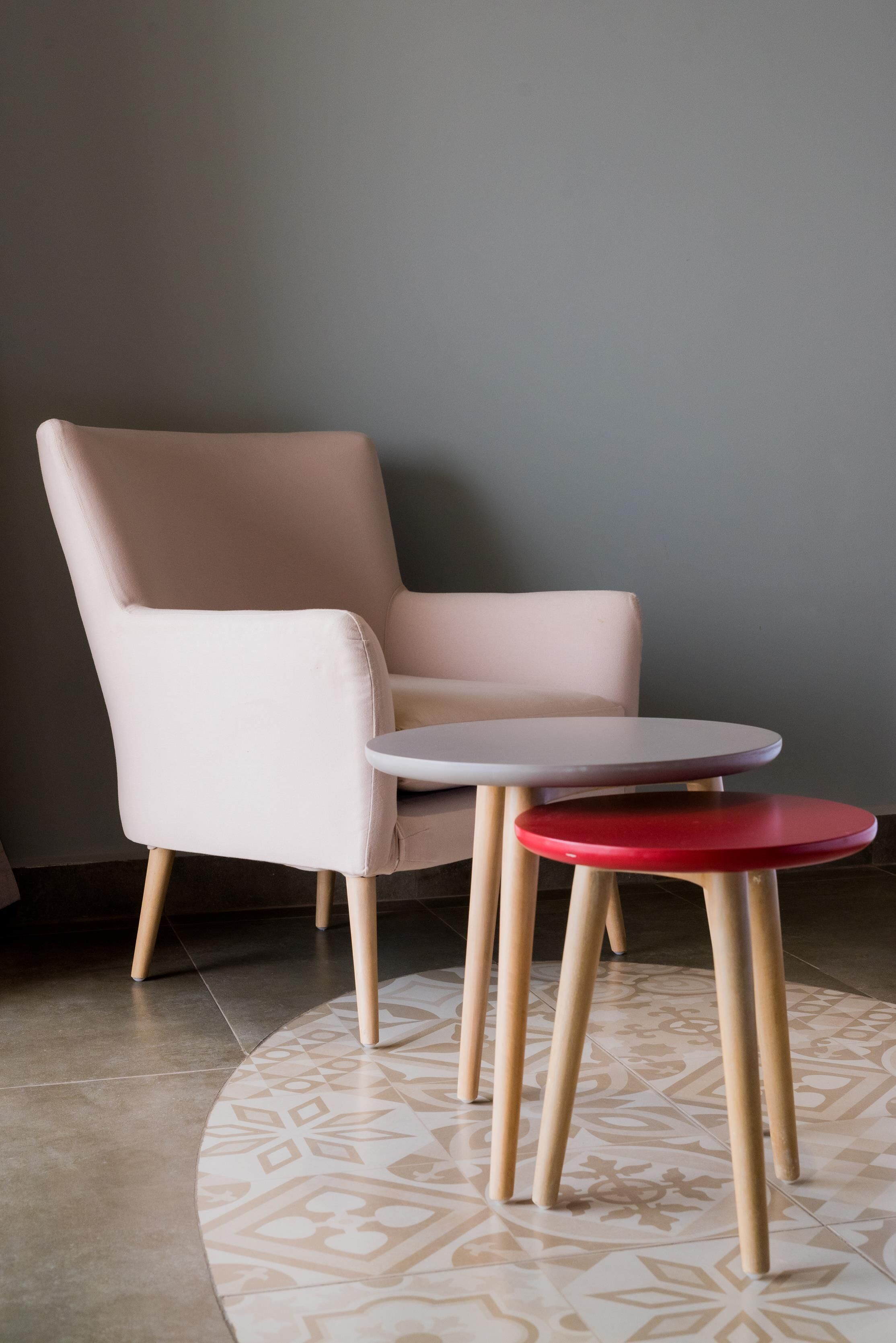 A room with a single chair and two tables, one with a red top and one with a white top.