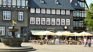 A cobblestone square with a fountain, outdoor seating at a cafe, and traditional half-timbered buildings. - Ferienwohnung Tuchtfeld (Goslar)