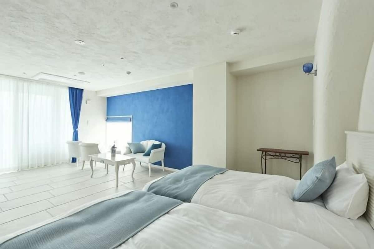 A hotel room with a large bed, a desk, a chair, and a view of the outdoors.