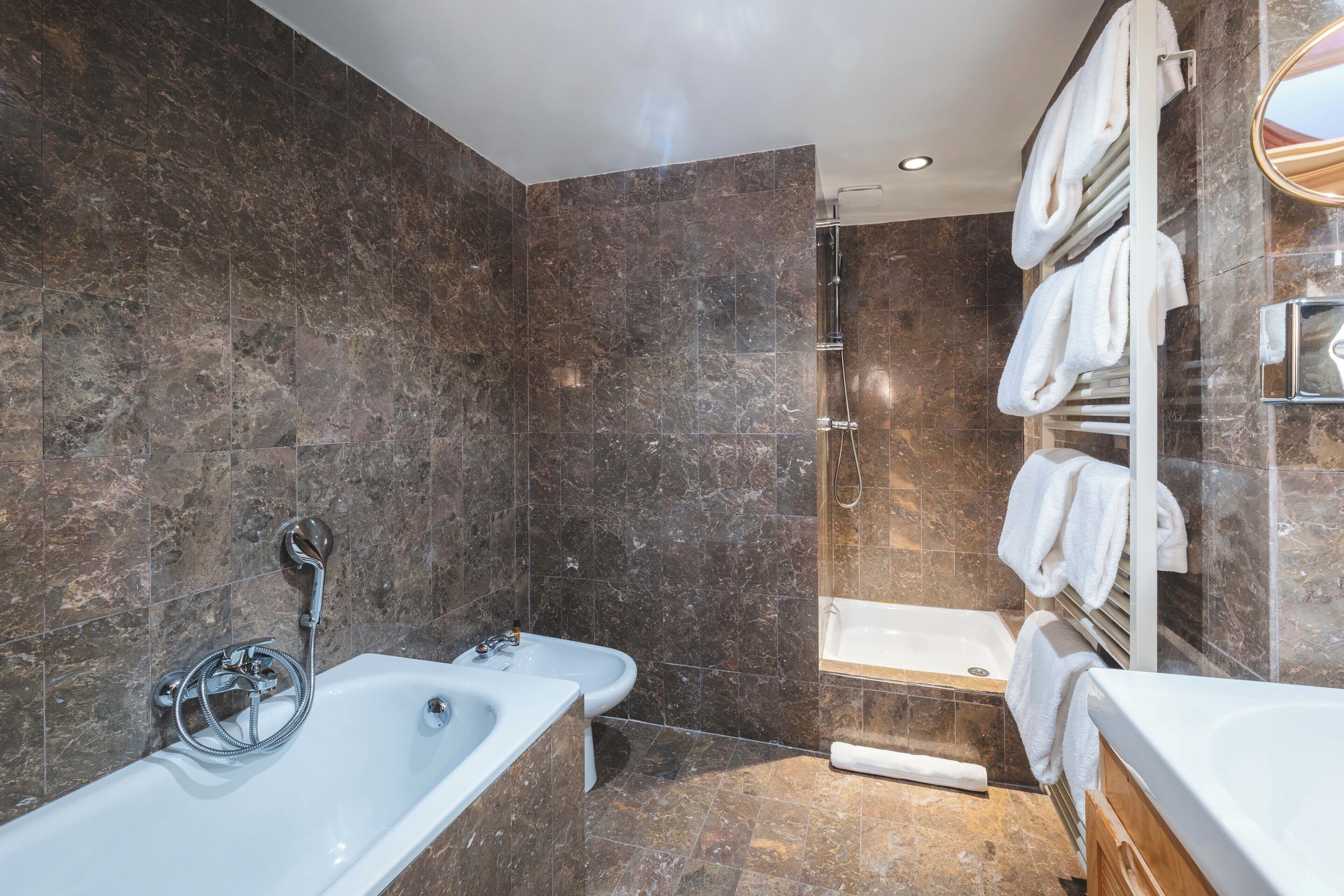 Un baño moderno con bañera, ducha e inodoro bidé. Se ven toalleros a la derecha.