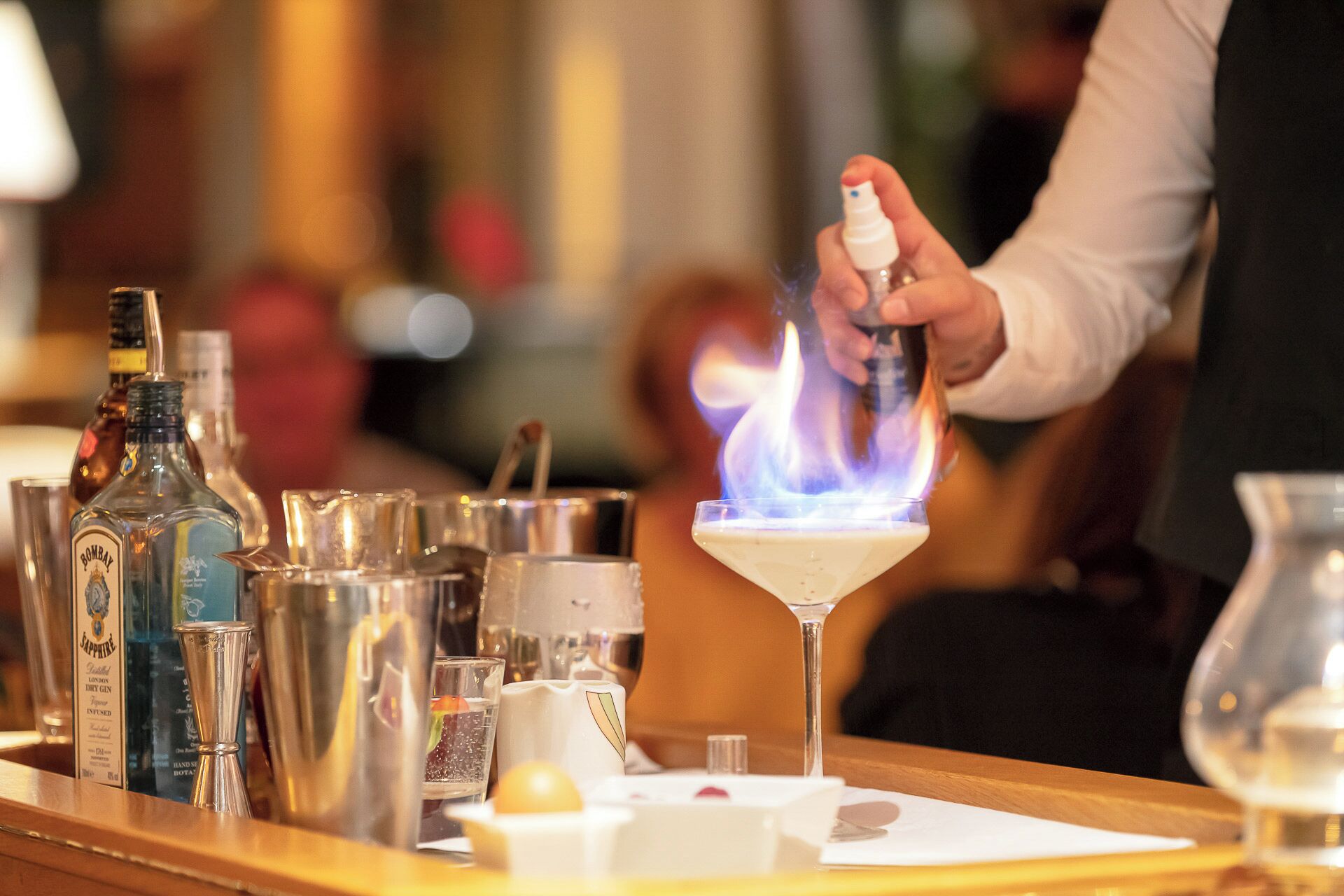 A bar setting with various bottles and a flaming cocktail.
